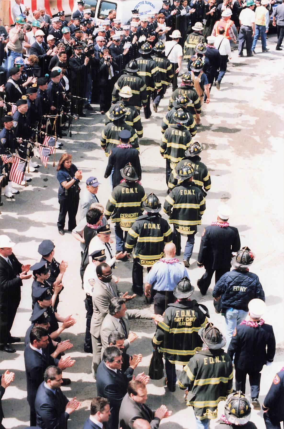 Firefighters march past an applauding crowd, May 2002